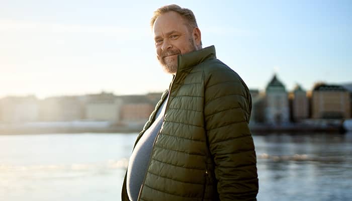  Man med obesitas som står vid vatten vid solnedgången 